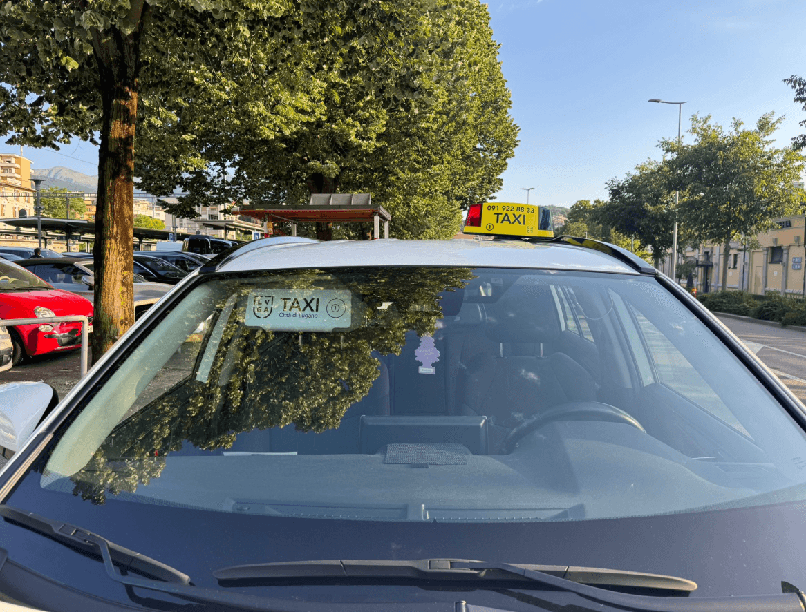 Taxi autorizzato Lugano — insegna luminosa e adesivo municipale